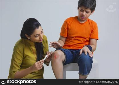 Mother putting bandage on sons wound