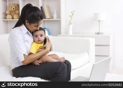 Mother putting mobile phone to babies ear