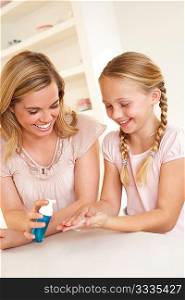 Mother putting sanitizer on young girl&acute;s hands