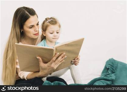 mother reading book cute girl bed