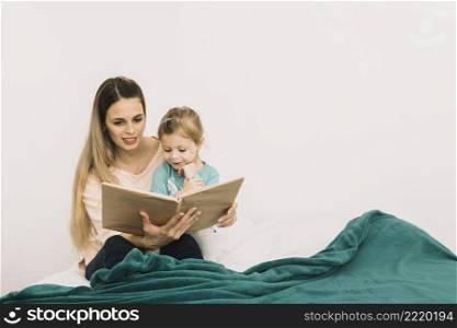 mother reading book daughter bed