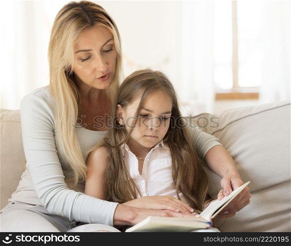 mother reading book daughter home