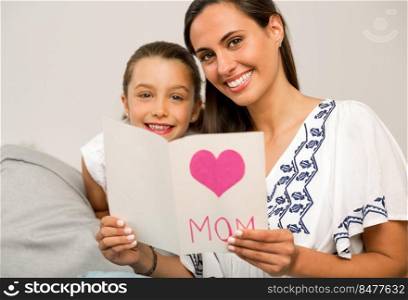 Mother receiving a greeting card on mother’s day from her daughter