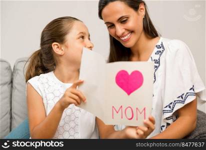 Mother receiving a greeting card on mother’s day from her daughter
