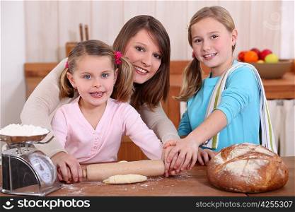Mother rolling dough with two daughters