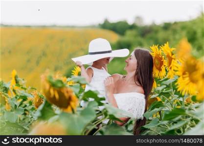 mother&rsquo;s day. Happy mother with the daughter in the field with sunflowers. mom and baby girl having fun outdoors. family concept. mother&rsquo;s day. Happy mother with the daughter in the field with sunflowers. mom and baby girl having fun outdoors. family concept.