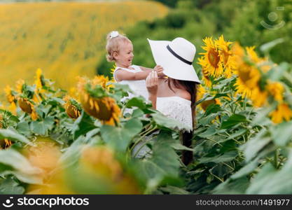 mother&rsquo;s day. Happy mother with the daughter in the field with sunflowers. mom and baby girl having fun outdoors. family concept. mother&rsquo;s day. Happy mother with the daughter in the field with sunflowers. mom and baby girl having fun outdoors. family concept.