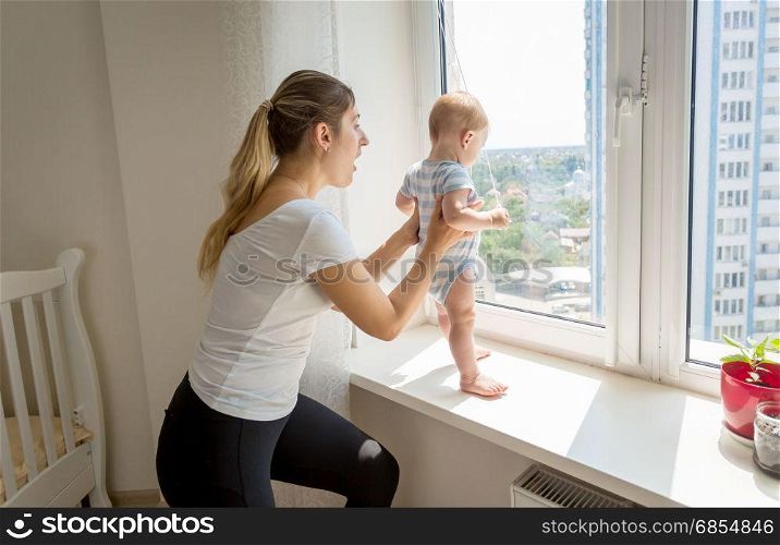 Mother rushing to her baby that is trying to open window