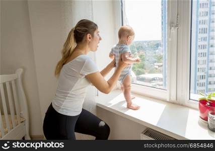 Mother rushing to her baby that is trying to open window