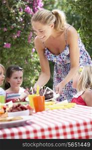 Mother Serving Birthday Cake To Group Of Children Outdoors