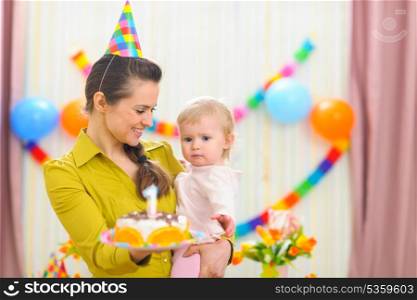 Mother showing baby birthday cake
