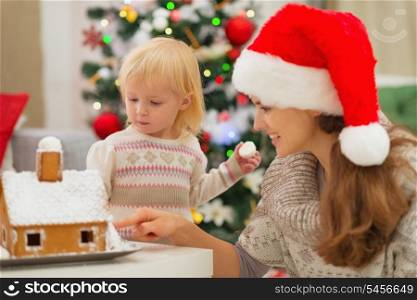 Mother showing baby Christmas Gingerbread House