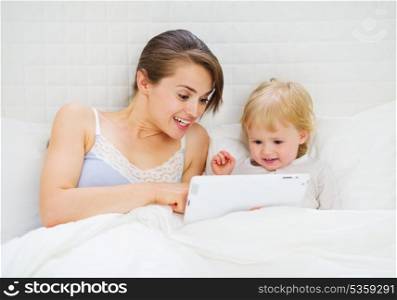 Mother showing something to baby in tablet pc
