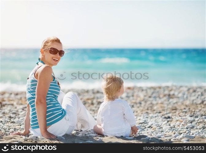 Mother sitting with baby on beach