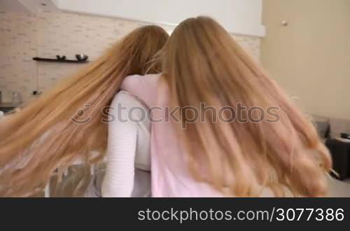 Mother smiles whirling her daughter piggyback at home