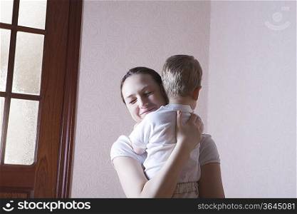 Mother smiles with happiness while hugging her son