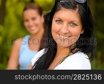 Mother smiling with teen daughter in background parenting outdoors relaxing