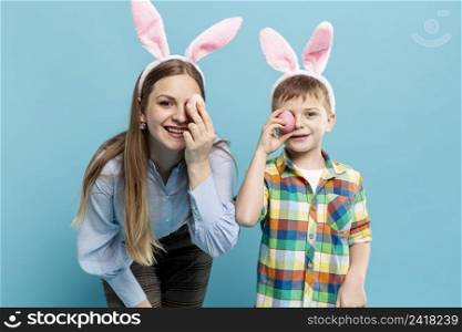 mother son with rabbit ears covering eyes with painted eggs