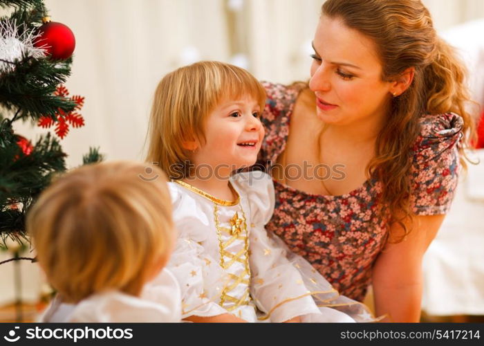 Mother spending time with daughters near Christmas tree