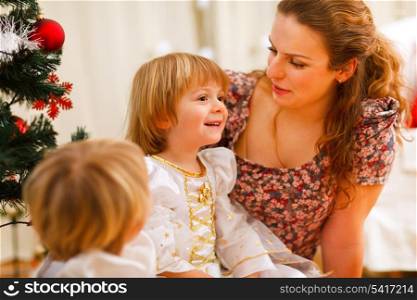 Mother spending time with daughters near Christmas tree