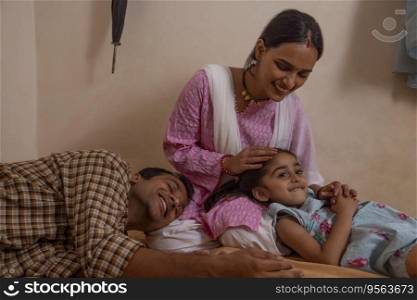 Mother stroking her daughter s head while her husband lying with head on her lap
