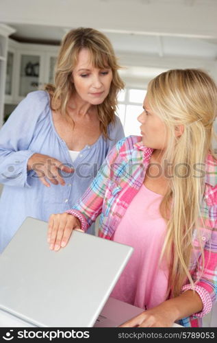 Mother supervising teenage daughter using laptop