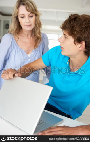 Mother supervising teenage son using laptop