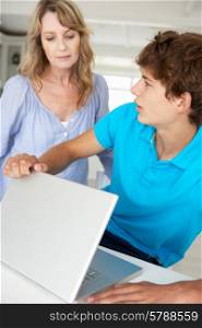 Mother supervising teenage son using laptop