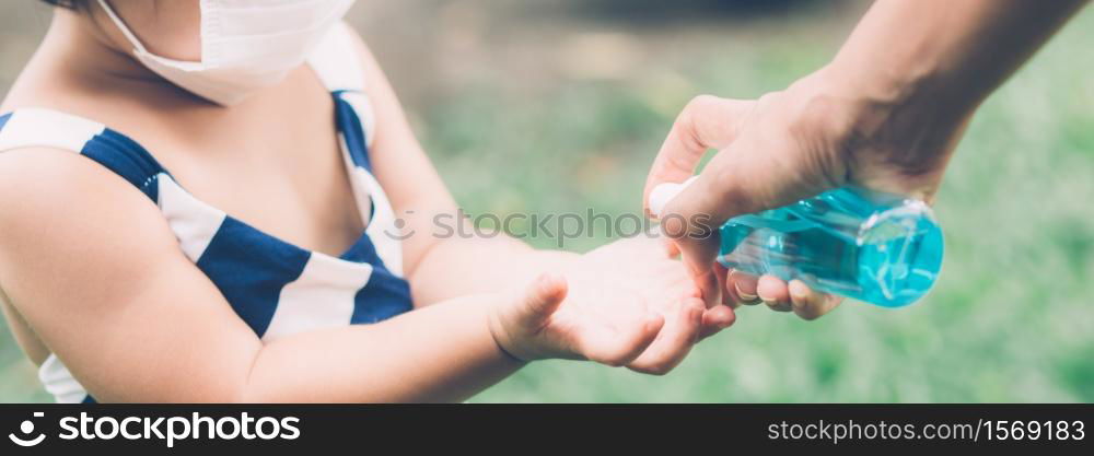 Mother take care daughter with face mask and sanitizer for protection disease flu or covid-19, mom and child wearing medical mask clean hand for safety for outbreak of pandemic, banner website.