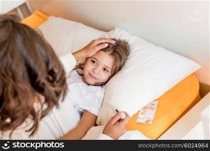 Mother taking care of her sick daughter in bedroom