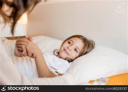 Mother taking care of her sick daughter in bedroom