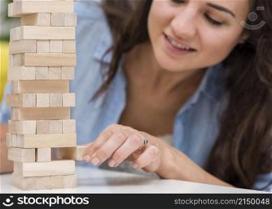 mother taking care while getting piece wooden tower game