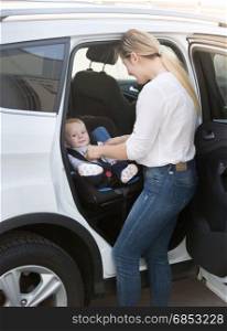 Mother taking her baby in safety seat out of the car