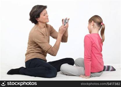 mother taking picture of young daughter isolated on white