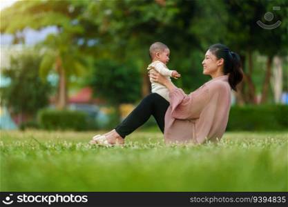mother talking and playing with her infant baby while sitting on a grass field