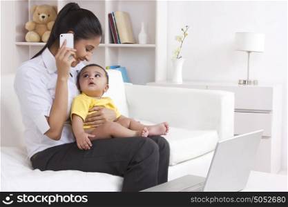 Mother talking on mobile phone while baby looks on