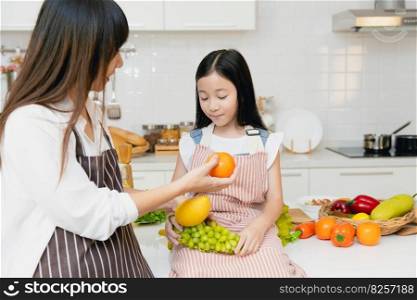 Mother teaching child to eating fruit and advise to eat orange for vitamin C and healthy food.