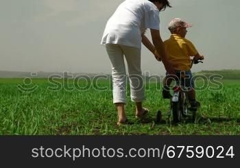 Mother teaching child to ride a bicycle