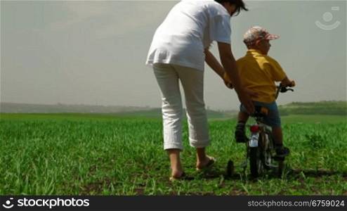 Mother teaching child to ride a bicycle