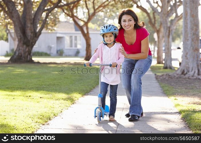 Mother Teaching Daughter To Ride Scooter