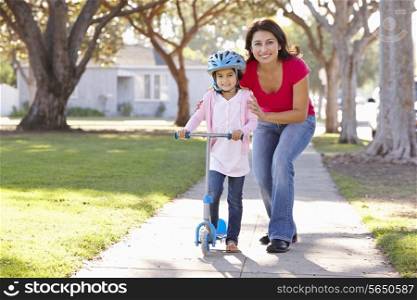 Mother Teaching Daughter To Ride Scooter