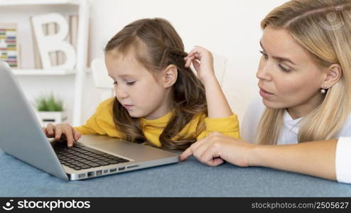 mother teaching her daughter how use laptop