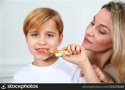 Mother teaching little boy to brush his teeth