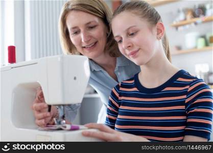 Mother Teaching Teenage Daughter How To Use Sewing Machine At Home