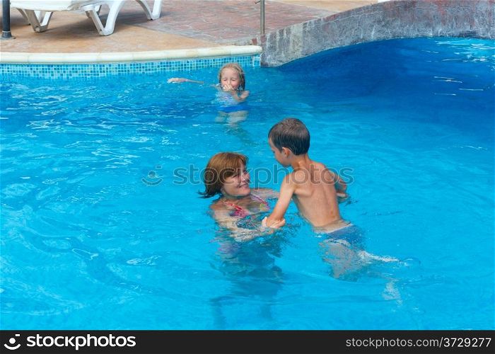 Mother train children to swim in the pool.