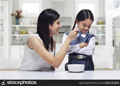 Mother trying to feed daughter breakfast