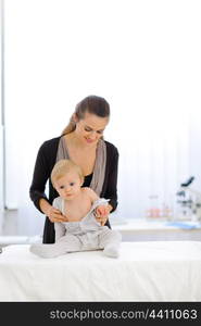 Mother undressing baby at pediatricians cabinet&#xA;