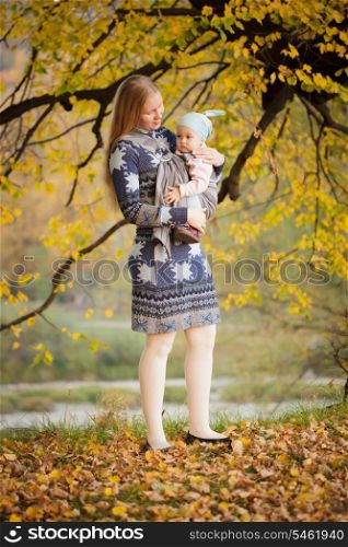 Mother walking with baby in sling in the park