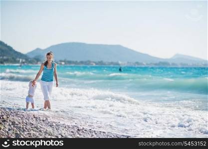 Mother walking with baby on seashore