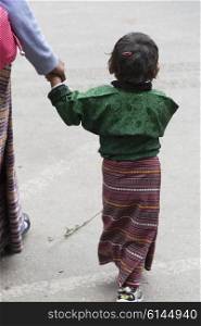 Mother walking with her little daughter on street, Thimphu, Bhutan